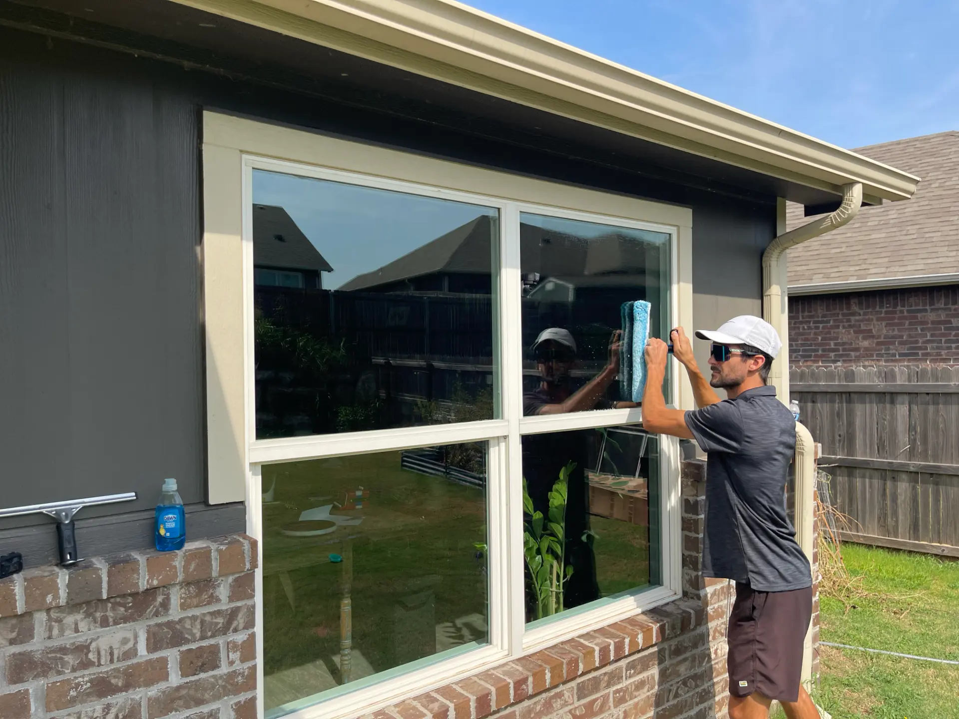 Scrubbing exterior window glass with a pole brush